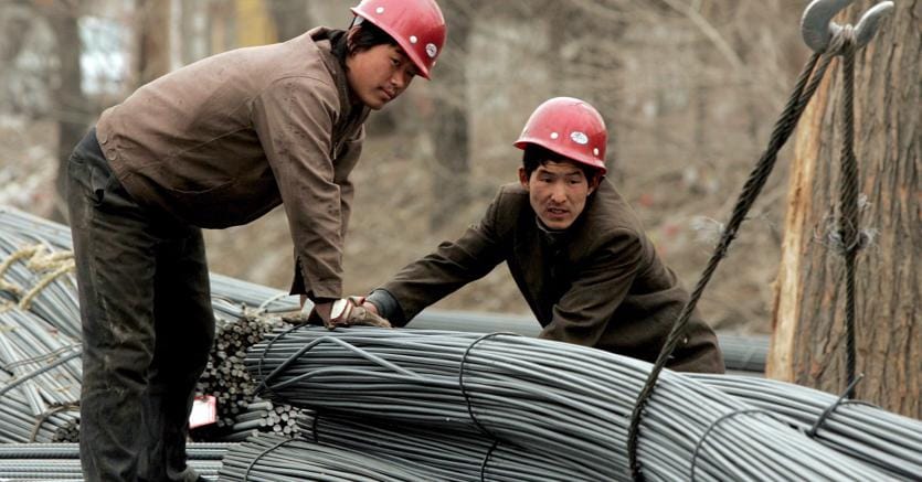 Operai cinesi a Beijing trasportano cavi di accaio (Ansa)