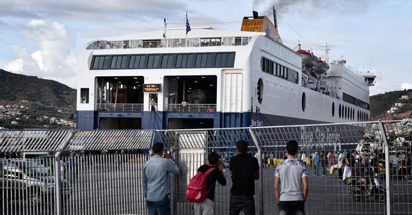 Un gruppo di profughi fuggiti dal campo incendiato di Moira guardano un ferry nel porto di Mitilene nell’isola di Lesbo.