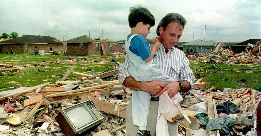 Un uomo con in braccio un bambino tra i resti degli edifici distrutti dall’uragano Andrew che nell’agosto del 1992 sconvolse in particolare Florida e Louisiana negli Stati Uniti (AFP Photo)