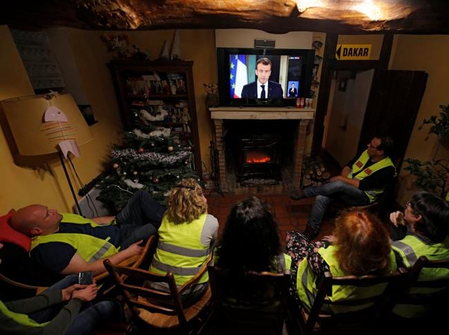 Alcuni Gilet gialli ascoltano il discorso di Emmanuel Macron (REUTERS)