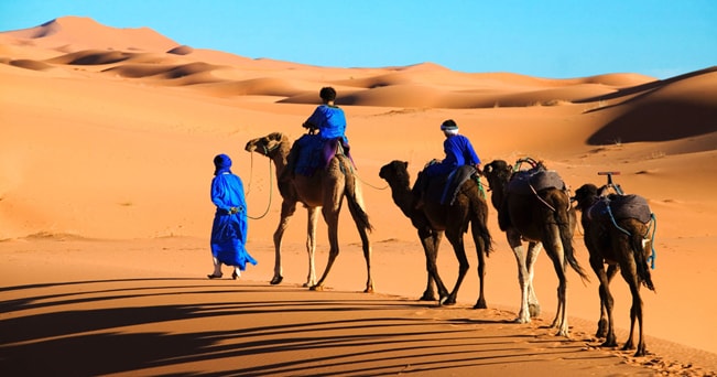 Un Tuareg e i suoi figli attraversano l'area di Erg Chebbi nel deserto del Sahara (foto Martin Harvey / Alamy / Milestone Media)