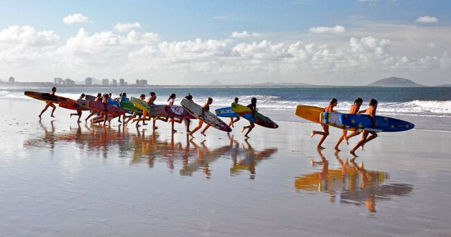 Surfisti in corsa verso l'oceano (foto Jennie Hart / Alamy)