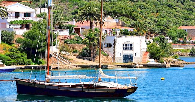 Una barca a vela ancorata in una baia di Minorca