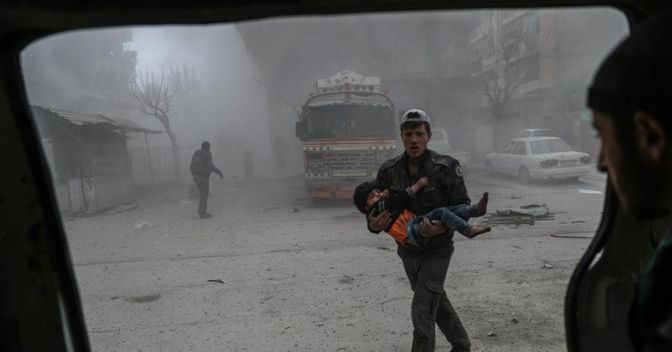 Un volontario soccorre un bambino nel Ghouta orientale, in Siria, sottoposto a massicci bombardamenti 