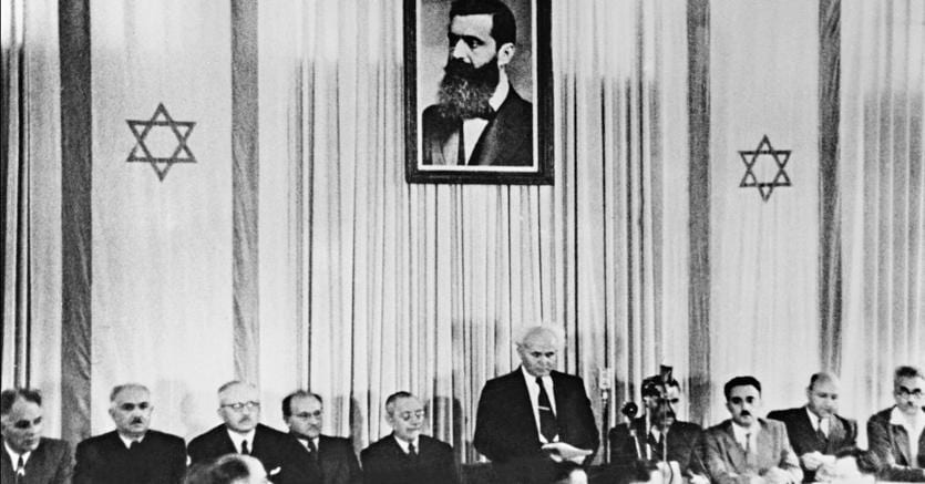 Il primo ministro David Ben Gurion, il 14 maggio 1948, dichiara l’indipendenza dello Stato d’Israele, a Tel Aviv. Alle sue spalle, il ritratto di Theodor Herzl, fondatore del sionismo politico