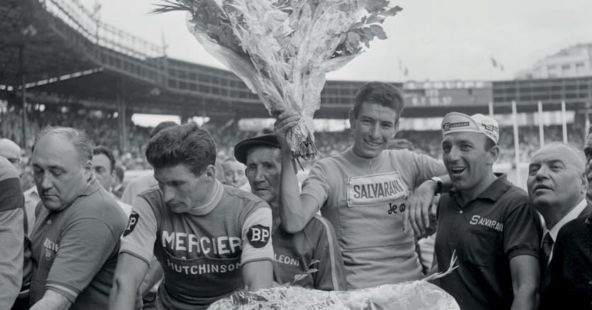 Felice Gimondi, trionfatore del Tour de France 1965 a soli 22 anni, solleva il mazzo di fiori destinato al vincitore.A sinistra, un corrucciato Raymond Poulidor, eterno secondo