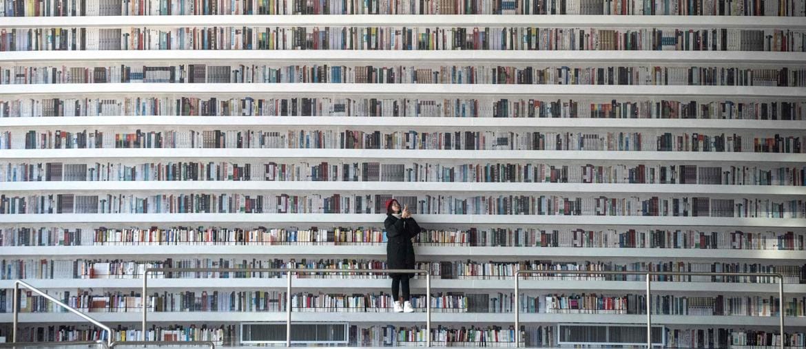 Perdersi
nella lettura . Una ragazza scatta foto nella Tianjin Binhai Library, l’avveniristica biblioteca caratterizzata dalle linee sinuose degli scaffali e da lunghe distese di libri