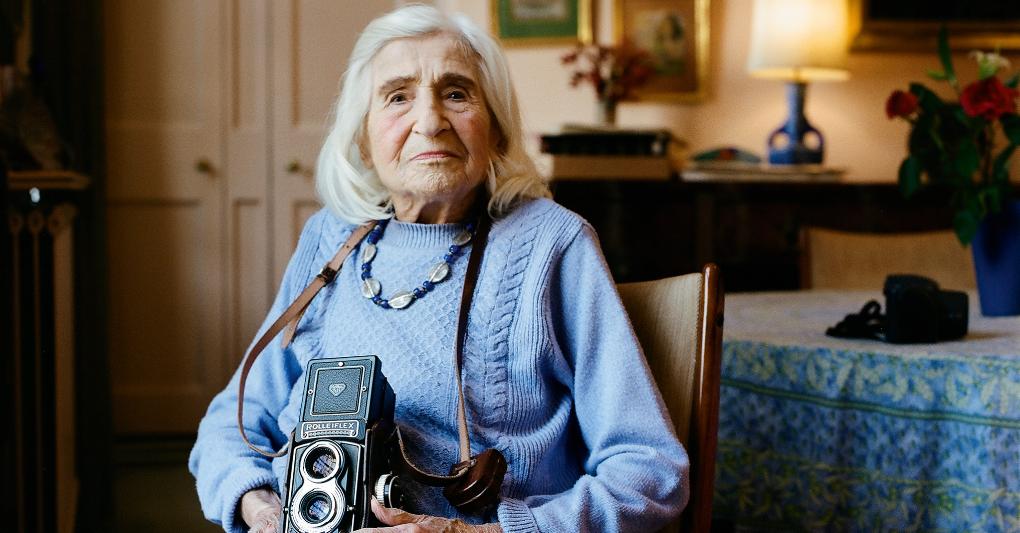 Dorothy Bohm nella sala da pranzo della sua casa di Hampstead, a nord di Londra. Tra le mani tiene la sua Rolleiflex. ©Lydia Goldblatt 