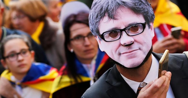 Un manifestante a Barcellona con la maschera del  leader catalano Puigdemont (Afp) 
