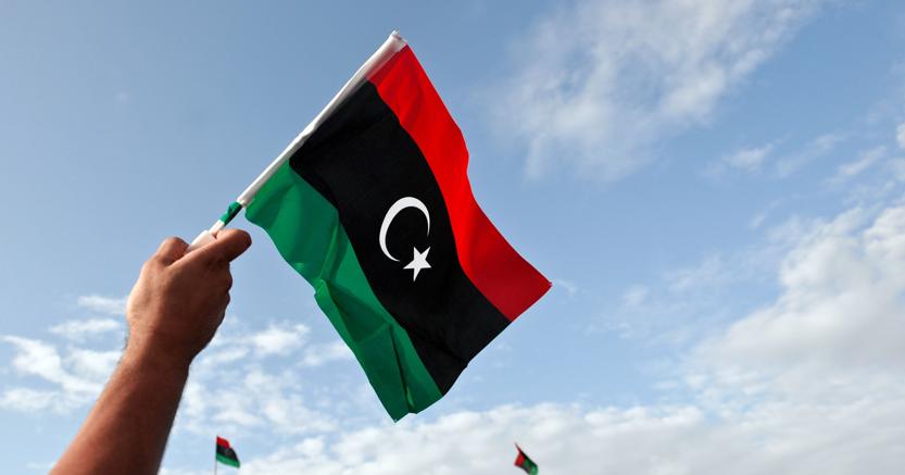 Un uomo sventola la nuova bandiera nazionale dopo la caduta di Gheddafi 