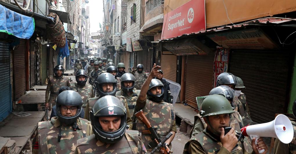Forze di sicurezza indiane marciano in uno dei quartieri teatro delle violenze che hanno sconvolto New Delhi negli ultimi giorni 