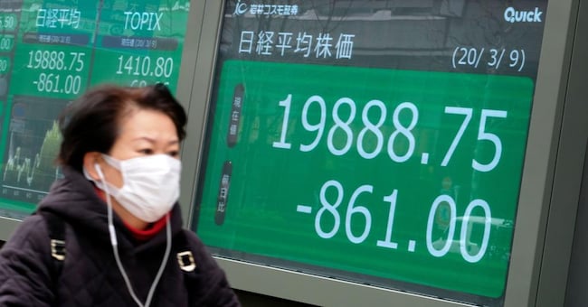 Una donna davanti a uno schermo con l’andamento della Borsa di Tokyo (Afp) 