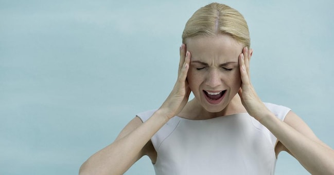 Woman holding head and screaming with eyes closed