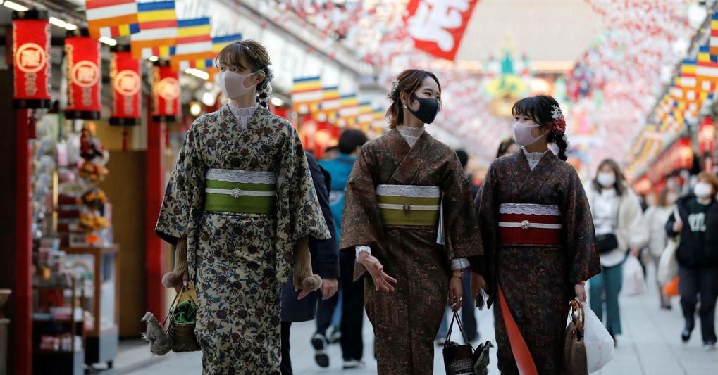Tre ragazze in costume tradizionale passeggiano sotto le decorazioni per l’anno nuovo. Tokyo è in allerta per i contagi di Covid-19 