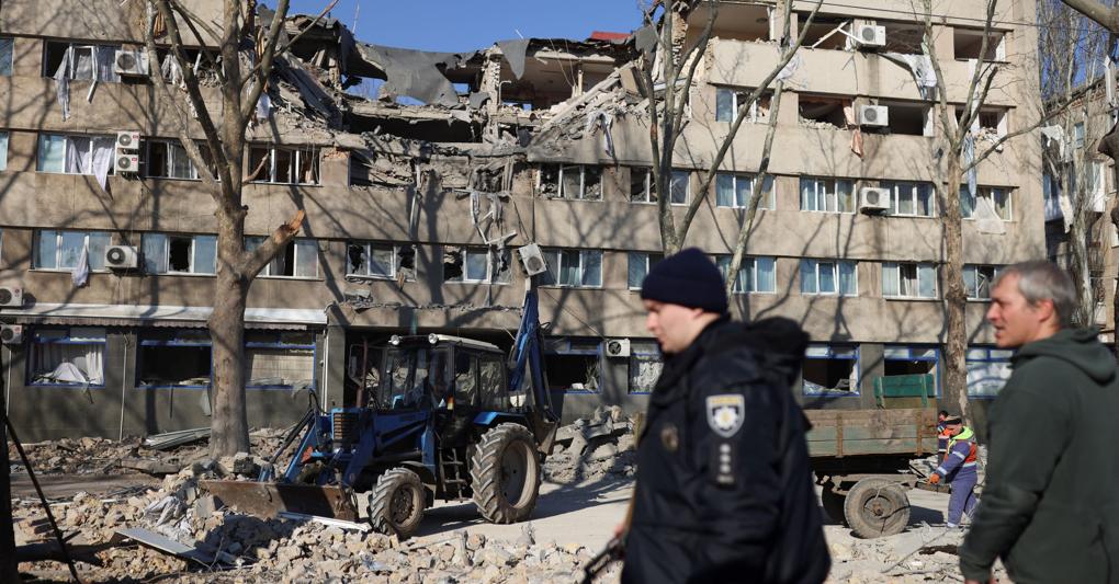 Mentre l’invasione russa dell’Ucraina continua, a Mykolaiv, la gente pulisce il marciapiede di fronte a un edificio danneggiato dopo un attacco militare. (REUTERS/Nacho Doce) 