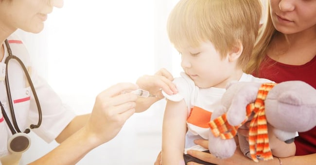 A doctor giving a child an injection at home.