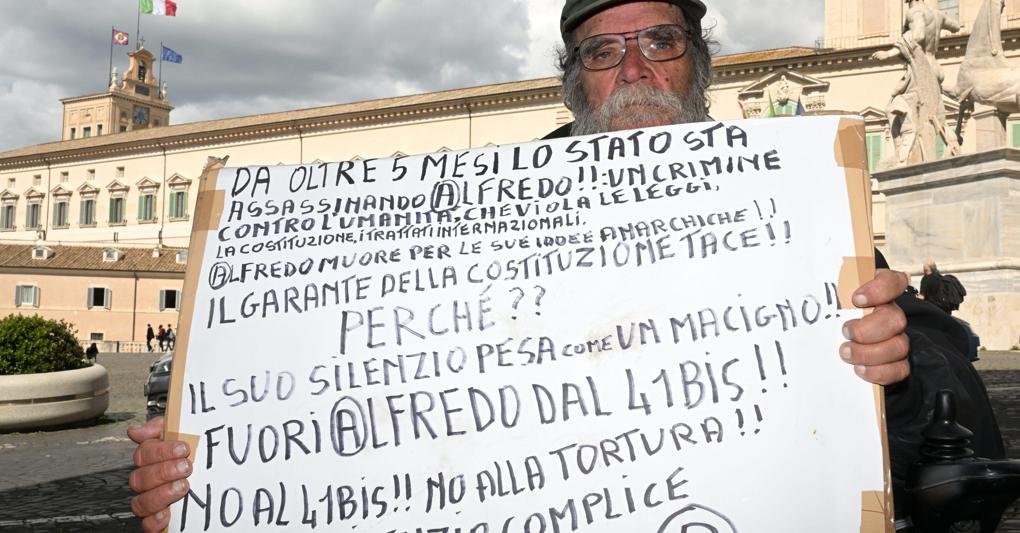 L’anarchico Pasquale Valitutti mostra un cartello in difesa di Alfredo Cospito durante la protesta nei pressi del Quirinale (Ansa) 