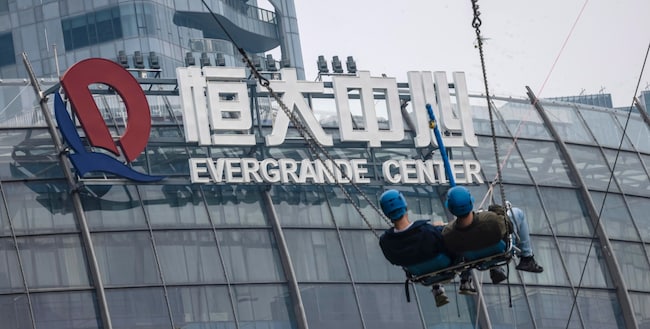 epa09538453 People ride on a swing in the amusement park in front of the Evergrande Center building in Shanghai, China, 22 October 2021. According to the state-owned media, China Evergrande Group, the world's most indebted property developer, made 83.5 million USD (71.72 million EUR) interest payment to an offshore dollar bond. For the first time in more than 6 years, new home prices in China fell in September compared with the previous month, according to China's National Bureau of Statistics report. Evergrande announced this week that sales of new apartments dropped by 97 percent over September and the first part of October in comparison with the previous year. EPA/ALEX PLAVEVSKI