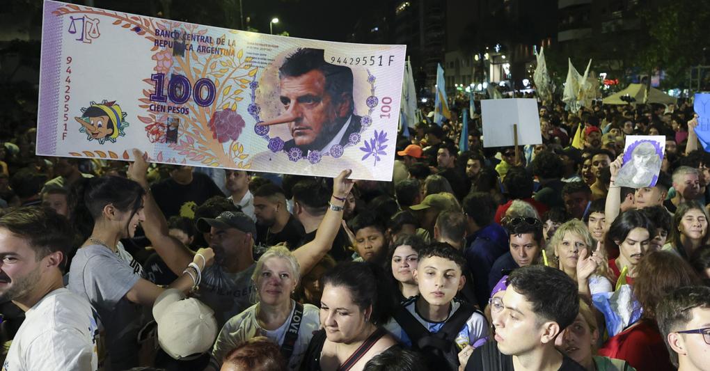 Cordoba. Al comizio di chiusura i sostenitori di Javier Milei, candidato per il partito “La Libertad Avanza” con un cartello che raffigura una banconota da 100 pesos e il rivale Sergio Massa, ministro dell’Economia, con il naso da Pinocchio 