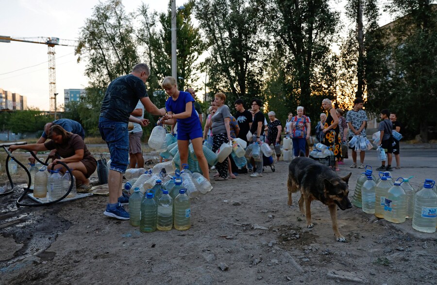 Le persone aspettano in fila per raccogliere l'acqua consegnata da un camion cisterna nel corso del conflitto militare tra Russia e Ucraina, a Donetsk, città dell'Ucraina controllata dai russi. (REUTERS/Alexander Ermochenko)