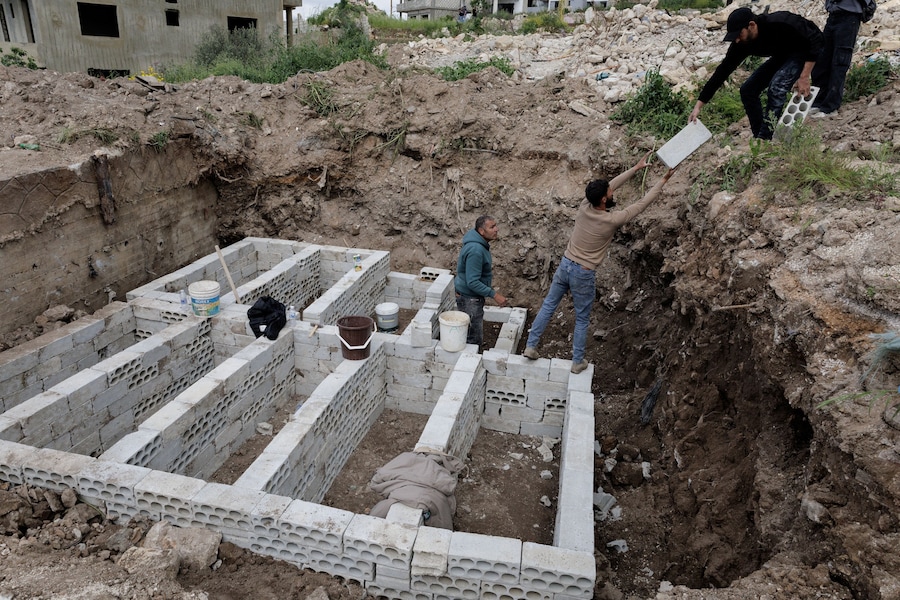 I membri della protezione civile preparano le tombe per accogliere i corpi di nove combattenti di Hezbollah, che saranno riesumati dalle tombe provvisorie per ricevere una sepoltura dignitosa nei loro villaggi d'origine, nel villaggio di Majdelzon, nel sud del Libano. (Reuters)
