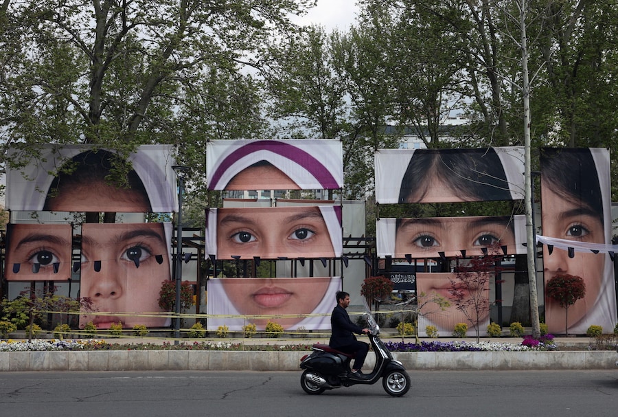 epa12905625 A person rides a motorcycle past portraits of schoolgirls killed in an airstrike in Minab, displayed at Tajrish Square in Tehran, Iran, 21 April 2026. US President Donald Trump announced that the ceasefire between the United States and Iran has been extended. EPA/ABEDIN TAHERKENAREH (Epa)