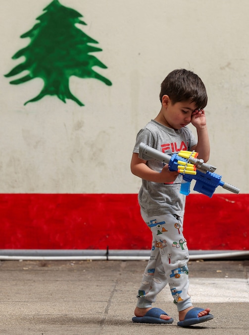 Un bambino, sfollato dal Libano meridionale a causa del conflitto con Israele, tiene in mano una pistola giocattolo mentre cammina in una scuola trasformata in rifugio, nei pressi di Sidone. (REUTERS)