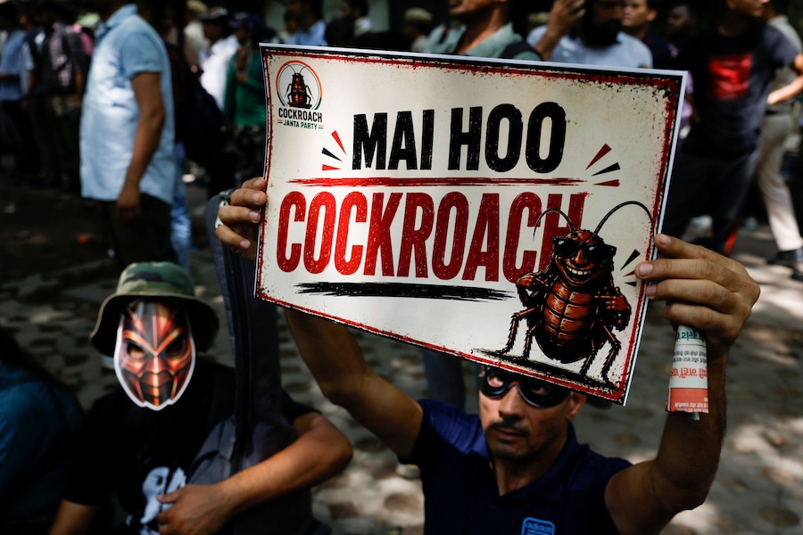 Una persona con indosso una maschera tiene in mano un cartello con la scritta «Sono uno scarafaggio», mentre i sostenitori del Cockroach Janta Party (CJP) attendono l’arrivo di Abhijeet Dipke, leader del CJP, nel giorno di un sit-in di protesta per chiedere le dimissioni del ministro dell'Istruzione indiano Dharmendra Pradhan, a Nuova Delhi, India, il 6 giugno 2026. REUTERS/Adnan Abidi (Reuters)