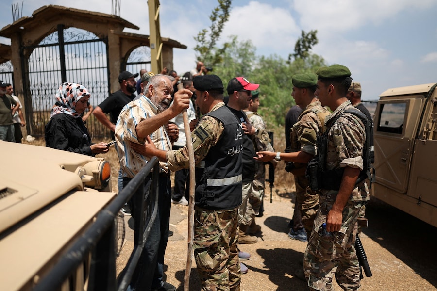 Un uomo parla ai soldati dell’esercito libanese che impediscono ai residenti di avanzare verso Zawtar al-Gharbiyeh, nel sud del Libano, e di superare il cordone di sicurezza che blocca l’accesso al villaggio per raggiungere le proprie case (Reuters)