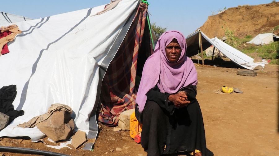 Una donna sfollata è seduta fuori dalla sua tenda in un accampamento di fortuna per sfollati a causa degli scontri tra i combattenti Houthi, alleati dell’Iran, e le forze governative yemenite sostenute dall’Arabia Saudita, nella provincia di Taiz, in Yemen (Reuters)