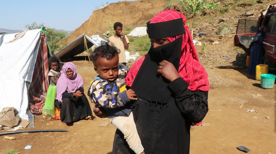 Una donna sfollata tiene in braccio un bambino in un campo di fortuna allestito per gli sfollati a causa degli scontri tra i combattenti Houthi, alleati dell’Iran, e le forze governative yemenite sostenute dall’Arabia Saudita, nella provincia di Taiz, nello Yemen (Reuters)