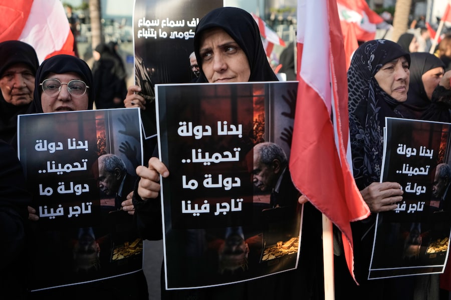 I sostenitori di Hezbollah espongono cartelli con la scritta in arabo “Vogliamo uno Stato che ci protegga, non uno che ci usi come merce di scambio”, durante una manifestazione contro il protrarsi del divieto di voli tra l’Iran e il Libano nel sobborgo meridionale di Beirut. (APS)