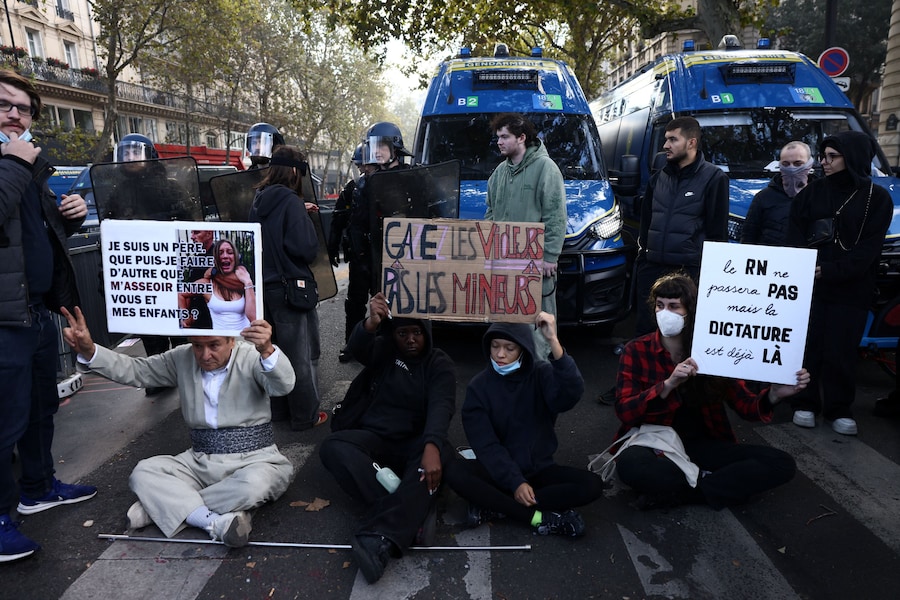 I manifestanti siedono davanti ai gendarmi francesi durante una manifestazione contro il costo della vita e l’aumento dei prezzi del carburante a Parigi (Reuters)