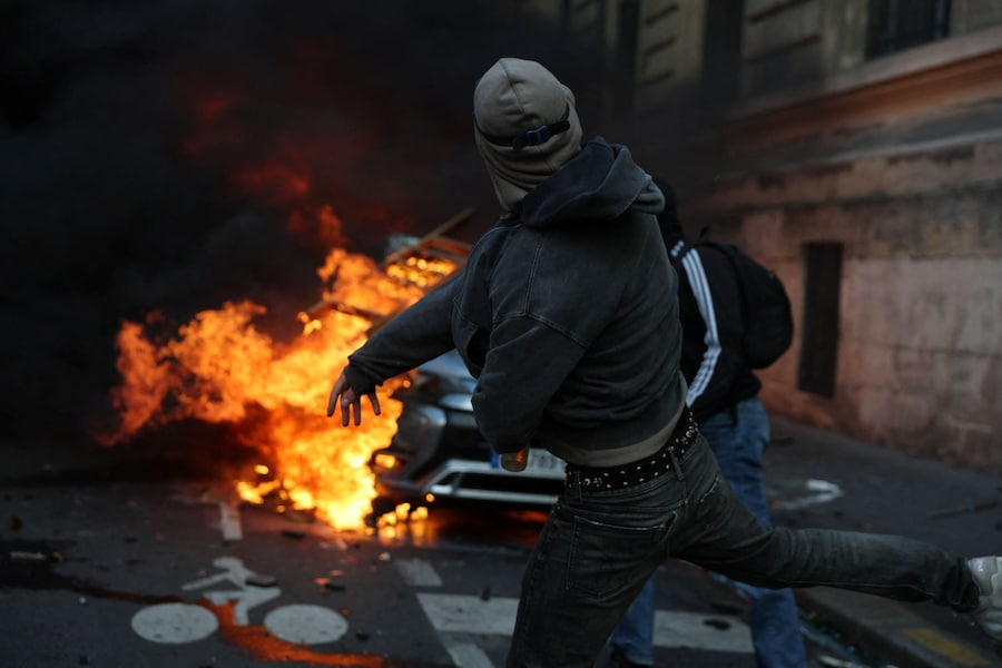 I manifestanti lanciano un oggetto contro un’auto in fiamme durante gli scontri scoppiati nel corso di una manifestazione contro il costo della vita e l’aumento dei prezzi del carburante nei pressi di Place de la République a Parigi, nell’ambito delle proteste nazionali indette dal movimento dei "Gilet Gialli", a cui si sono uniti studenti delle scuole superiori e universitari francesi, insegnanti e genitori che chiedono migliori condizioni scolastiche e un intervento del governo, nonché sindacati, lavoratori, agricoltori e pensionati, Francia, 17 ottobre 2026. (Reuters)