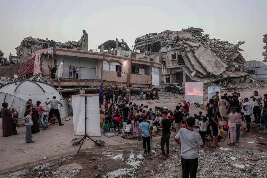 Bambini palestinesi sfollati all’interno del proprio Paese guardano un film in un cinema all’aperto improvvisato vicino alle rovine di edifici distrutti nel quartiere di Al-Sheikh Redwan a Gaza City (Epa)