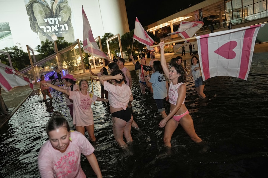 La gente sventola bandiere mentre cammina nell'acqua di uno specchio d'acqua per festeggiare i primi risultati degli exit poll relativi alle elezioni generali israeliane a Tel Aviv, Israele, martedì 27 ottobre 2026. (Foto AP/Oded Balilty) (APN)