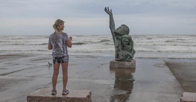 Una donna scatta una foto della statua della Grande Tempesta del 1900 sul Galveston Seawall mentre le onde dell’uragano Laura si abbattono il 26 agosto 2020 a Galveston, Texas.(Foto di Thomas B. Shea / Getty Images North America / Getty Images tramite AFP)