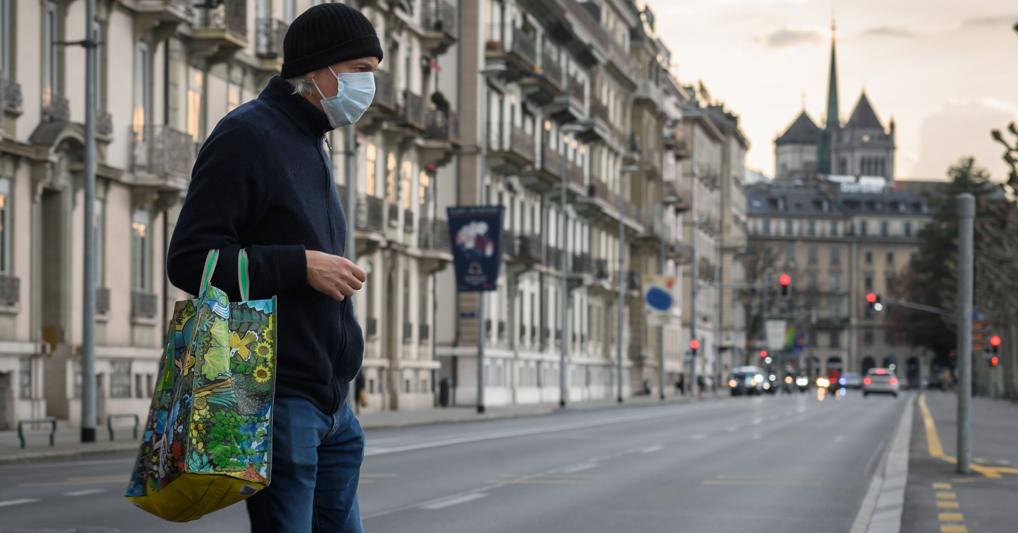A Ginevra un uomo con la mascherina attraversa la strada di fronte alla Cattedrale di Saint-Pierre. (Afp) 