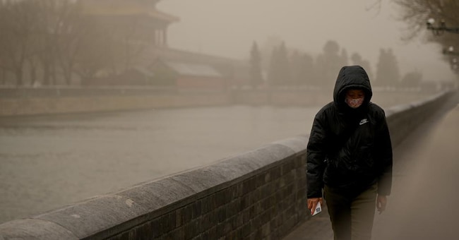 Piano quinquennale. L'obiettivo cinese è duplice: -18% di intensità energetica e -14% di emissioni entro il 2025. Nella foto una donna nella Città proibita a Pechino durante una tempesta di sabbia