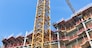 Construction site of apartment building with big yellow crane and blue sky