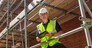 Male builder foreman, construction worker, contractor or architect on building site writing on black clipboard
