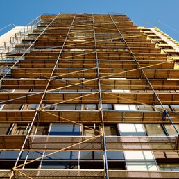 High building under construction bottom up view. Unfinished apartments house with scaffold