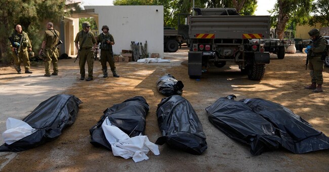 Militari israeliani davanti alle vittime del kibbutz Kfar Azza