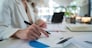 Close-up portrait of businesswoman accountant using calculator and laptop for matching financial data saving in office room, Business financial, tax, accounting concept
