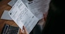 Close-up of female hands with pay slips, utility bills, account statements, payment receipts. A woman makes a count of household, family expenses with a calculator at home on the table.