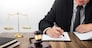 lawyer hand writes the document in court (justice, law) with sounding block and golden Weight.