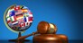 International law systems, justice, human rights and global business education concept with world flags on a school globe and a gavel on a desk on blue background.