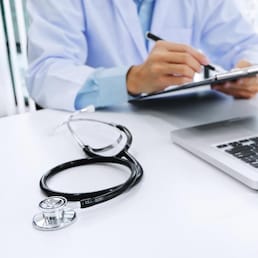 doctor working on laptop with  stethoscope and paper clipboard, selective focus