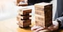 Planning, risk and wealth strategy in business concept, businessman and insurance gambling placing wooden block on a tower.