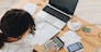 Top view of a woman working at home in the kitchen with financial papers, counting on a calculator, paying bills, planning a budget to save some money. Independent accounting, remote accountant.